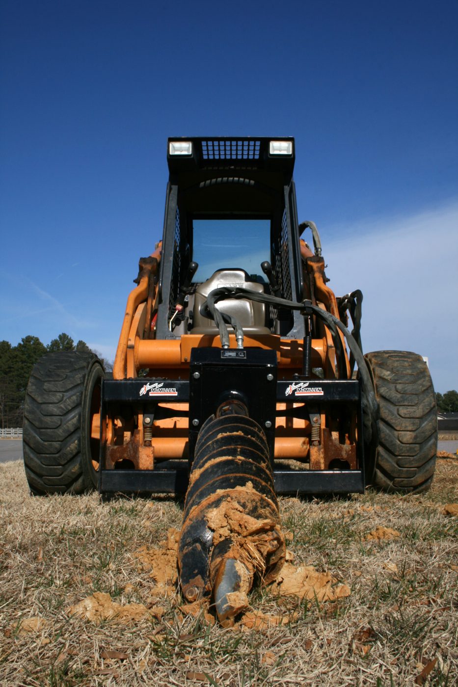 Skid steer with auger attachment drilling post holes